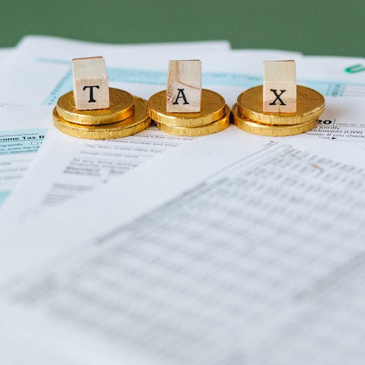 pexels-photo-6863176-6863176 Staged image of gold coins with tax letter tiles on documents.